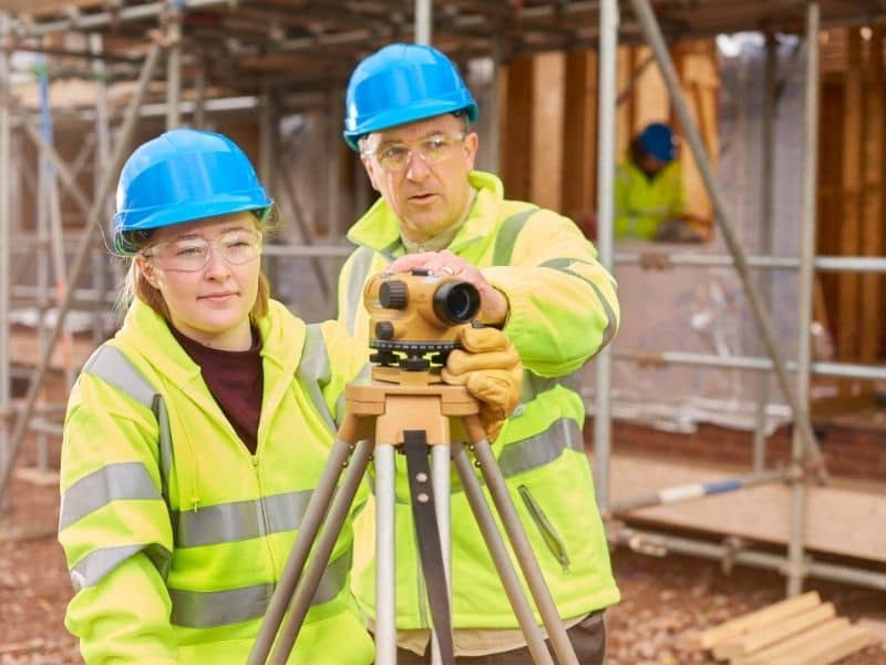 construction surveyors using a level instrument to support scheduling and layout on an active jobsite